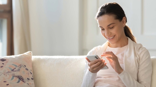 Lächelnde Frau sieht auf ihr Smartphone
