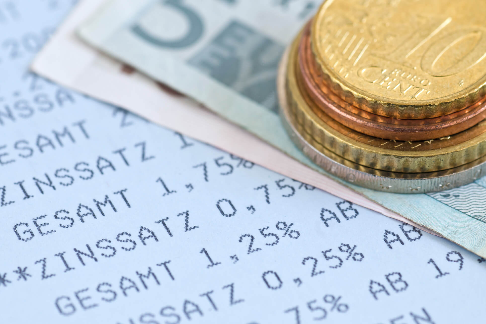 Bild mit Geldscheinen, Euro-Stücke und Bon mit Aufschrift: Zinssatz Zinssätze und Geld